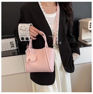Pink lychee grain bucket bag with cute elephant charm shown in a modern home setting