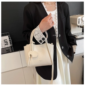 Detail of cream lychee leather bucket bag with cute elephant charm and branded lettering