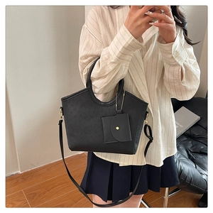 Detail view of black embossed tote bag with detachable coin purse and shoulder strap