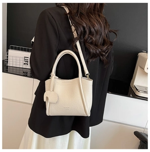 Detail of soft lychee grain leather bucket bag with cute elephant charm in beige