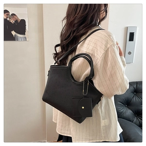 Detail view of black embossed leather tote bag with round handle and mini pouch attachment