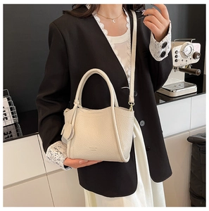 Detail of creamy white litchi pattern leather bucket bag with top handle and strap
