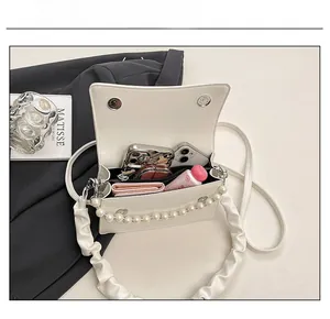 Internal view showing capacity of beige crossbody bag with pearl strap and essentials