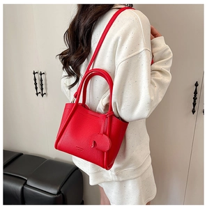 Detail of red lychee grain leather bucket bag with top handles and a detachable shoulder strap