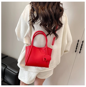 Detail of red pebbled leather bucket bag featuring a cute elephant charm and crossbody strap