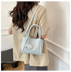Detail of light blue lychee pattern leather bucket bag with cute elephant charm