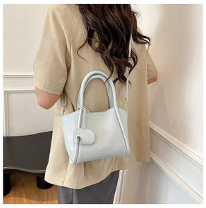 Close-up of light blue pebbled leather bucket bag with elephant charm and gold branding