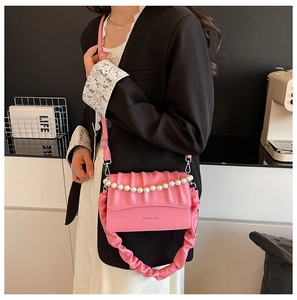 Pink ruched handbag with pearl chain handle and matching shoulder strap on a model