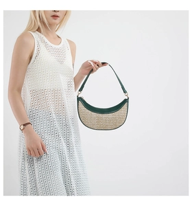 Detail of half-moon straw shoulder bag with dark green leather trim and gold hardware