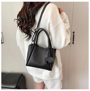 Detail of black pebbled leather bucket bag showing adjustable strap and texture