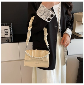 Chic cream small square bag with pearl chain strap and pleated handle detail on model