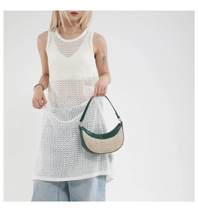 Detail of hand-woven straw shoulder bag with dark green leather trim and short handle
