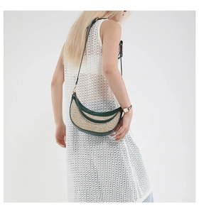 Detail of a woven crescent bag with green leather trim worn on a white crochet dress