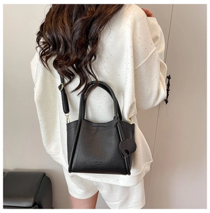 Detail of black lychee grain leather bucket bag with top handles and adjustable strap