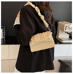 Detailed view of beige ruched handbag featuring elegant pearl chain and soft PU leather