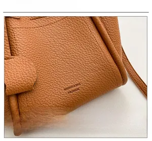 Close-up of caramel lychee grain leather finish and decorative side lettering on handbag
