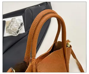 Detail of the brown lychee-patterned leather handles with precise contrast stitching
