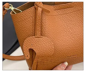 Detailed close-up of brown litchi grain leather bag with a cute elephant charm