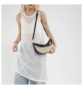 Fashionable straw shoulder bag with black leather trim worn by a model in a casual outfit