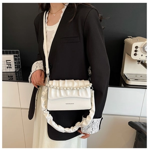 Detail of white pleated handbag featuring pearl embellishments and a FASHION & BAGS logo