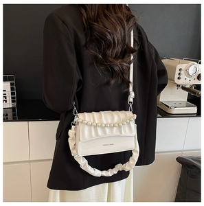 White ruched leather crossbody bag with pearl chain detail shown in a lifestyle setting