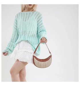 Detail of a brown leather and straw patchwork crescent bag with a summer knit outfit