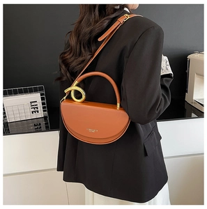 Detail of caramel brown saddle bag with golden circular handle and adjustable strap
