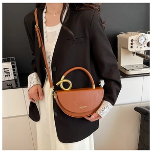 Detail of a brown semi-circle leather handbag with gold metal ring and shoulder strap