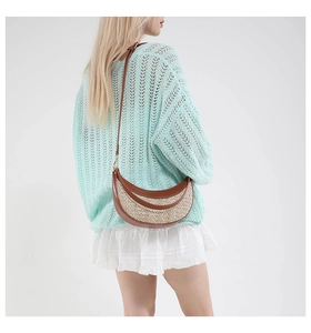 Detail of hand-woven straw crossbody bag with adjustable leather strap on model