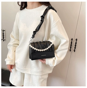 Detail of black pleated crossbody bag featuring pearl chain and wide ruched shoulder strap