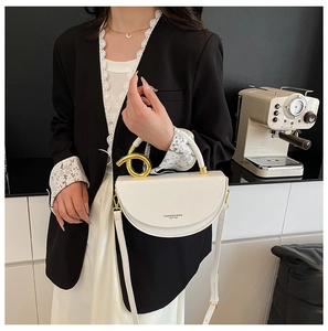 Detail of white half-moon leather bag with golden knot handle and adjustable strap