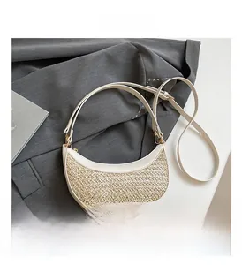 Detailed close-up of straw woven crescent bag featuring cream leather trim and gold hardware