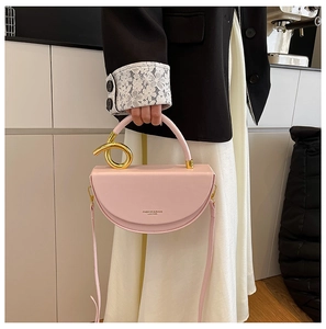 Detail of pink semi-circular handbag featuring golden knot accent and adjustable strap