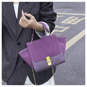 Detail of purple handbag with frosted suede flap, crocodile texture, and gold hardware