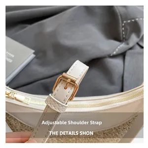 Detail of adjustable cream leather strap with gold buckle on woven crescent bag