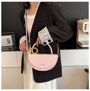 Pink crescent shoulder bag with a gold metal ring handle shown on a model