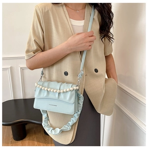 Detail of light blue crossbody bag featuring pearl chain and ruched shoulder strap