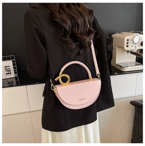 Close-up of pink half-moon saddle bag with a large golden twisted ring handle detail