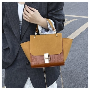 Close-up of retro wing bag featuring matte ginger suede and brown crocodile texture