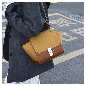 Detail of color-block crossbody bag featuring yellow suede and crocodile texture finish