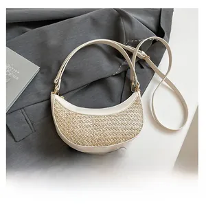 Close-up of woven straw and white leather crossbody bag with adjustable gold buckle