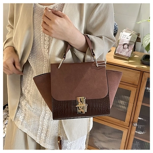 Detail of vintage wing bag with matte patchwork and crocodile pattern in dark brown