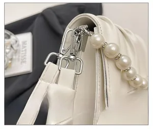 Close-up of silver metal hook and pearl bead chain strap on cream pleated crossbody bag