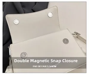 Detail view of double magnetic snap closure on a white leather textured crossbody bag