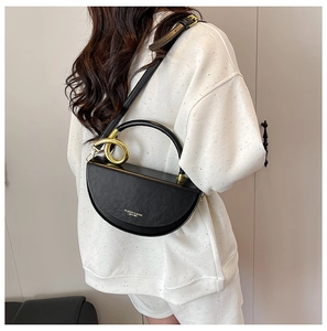 Detail of black leather half-moon bag featuring gold ring handle and adjustable strap