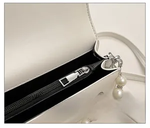 Detail view of the silver zipper and white pearl chain strap on the stylish handbag