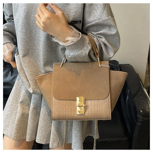 Detail of crossbody bag featuring khaki suede flap and crocodile texture lower panel