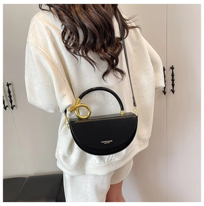Detail of black leather saddle bag with gold metal ring handle and fashion lettering