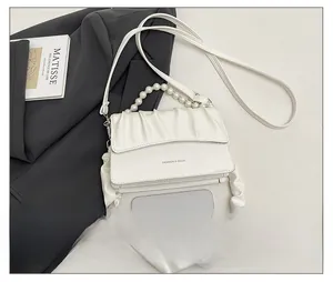 Detailed view of white ruched crossbody bag with pearl chain and smartphone for size scale