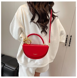 Close-up of red leather half-moon bag featuring a gold circular handle and logo